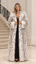 Front full view of woman wearing white spotted faux fur maxi coat over black dress