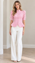 Front view of model wearing blush pink floral lace peplum blouse with white wide leg trousers