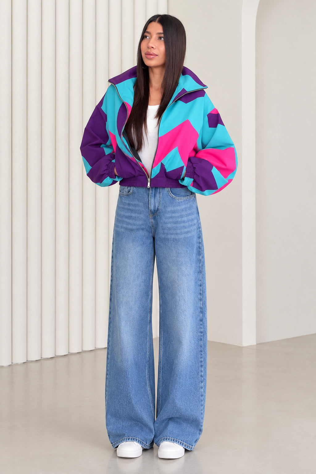 Front full view of woman wearing purple and turquoise retro colorblock windbreaker jacket with wide-leg jeans