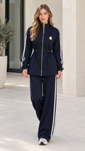 Front full view of woman wearing navy blue 2-piece zip tracksuit set with white side stripes