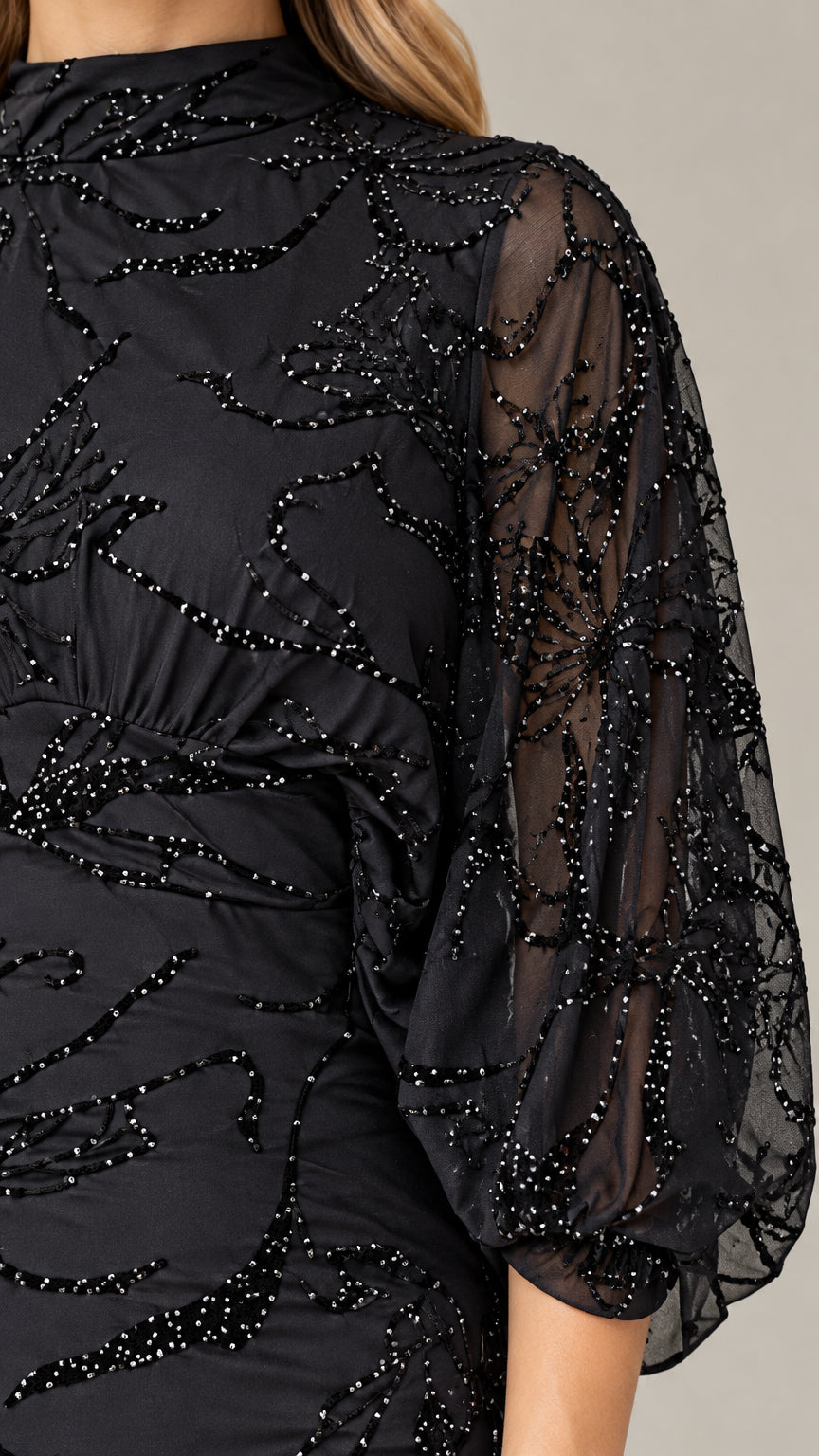 Close-up detail of sheer beaded sleeve and mock neckline craftsmanship